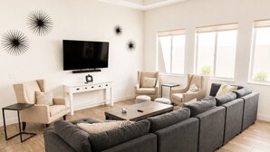 Un salon moderne avec un canapé d’angle, un téléviseur à écran plat et une table basse.
