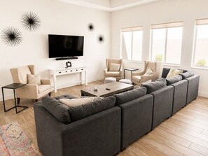 Una sala de estar moderna con un sofá modular, un televisor de pantalla plana y una mesa de centro.