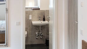Een moderne badkamer met een wastafel, spiegel en toilet.