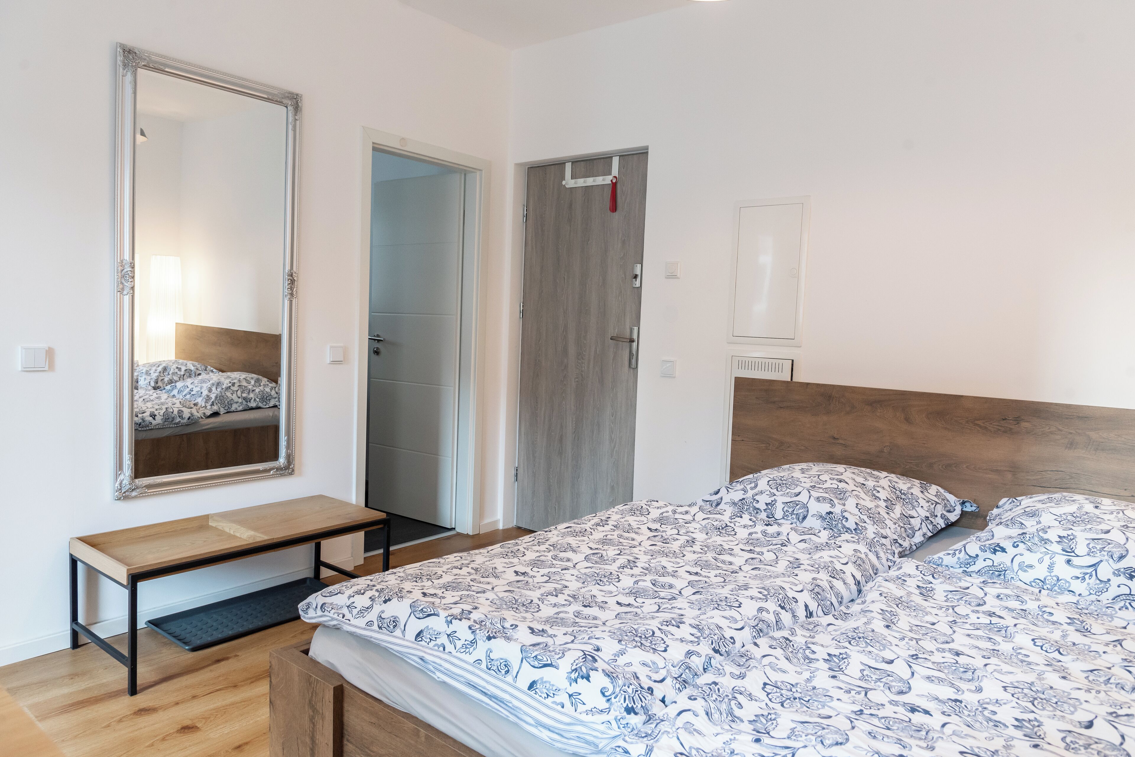 Un dormitorio con cama, cabecera de madera, mesita de noche, espejo y armario.