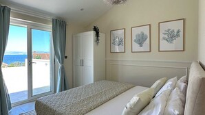 A bedroom with a bed, a wardrobe, a view of the sea, and three framed pictures on the wall. - Villa Sea Whisper - location and charm by MyWaycation (Splitska)