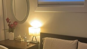 Habitació d'hotel amb un llit, una taula, una cadira, una làmpada, un mirall i una televisió.