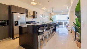 Una cucina moderna con isola centrale, elettrodomestici in acciaio inossidabile e sgabelli da bar.