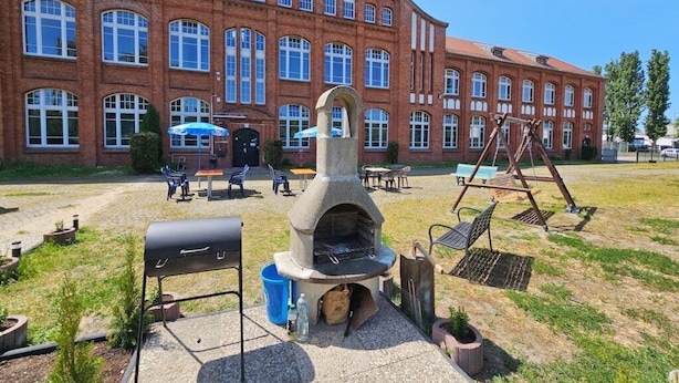 A courtyard with a stone-built outdoor oven, a barbecue grill, and outdoor seating. - Motel Home Wittenau (Berlin)