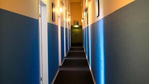 A hotel hallway with blue and white walls, doors, and a carpeted floor. - Motel Home Wittenau (Berlin)