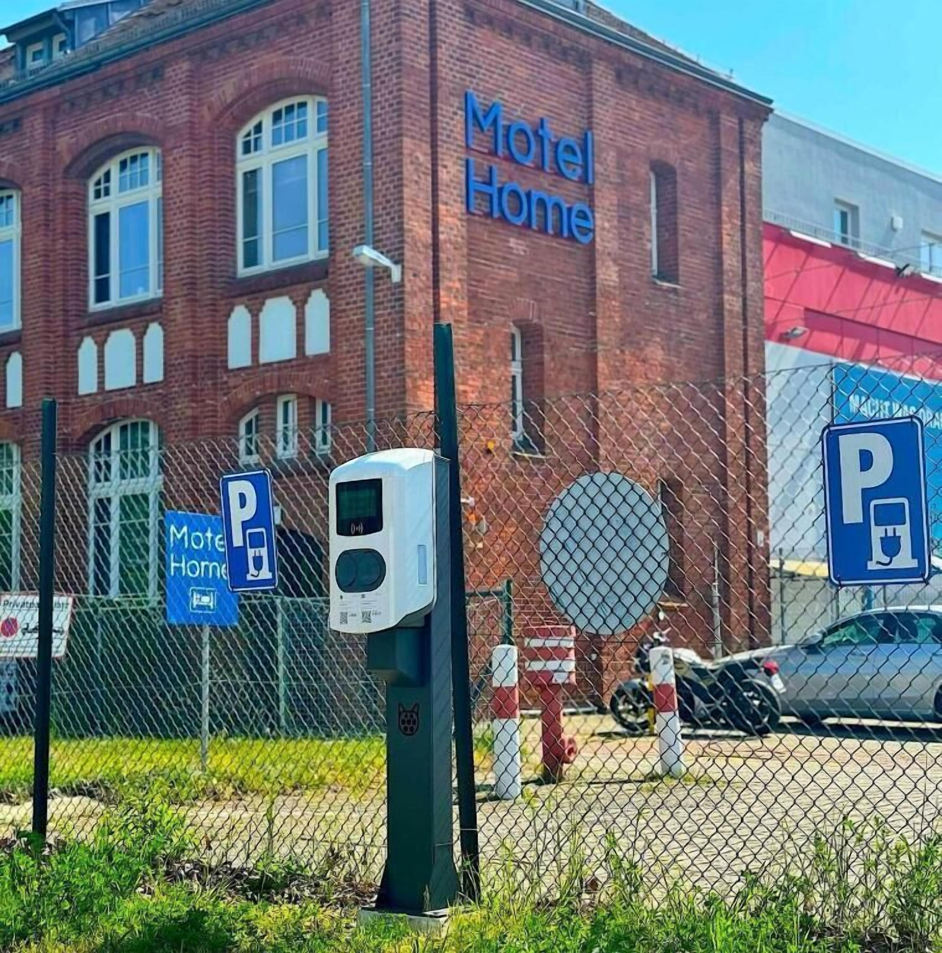 Un edificio de ladrillo con un letrero que dice "Motel Home" y un cartel de estacionamiento que indica un área de estacionamiento.