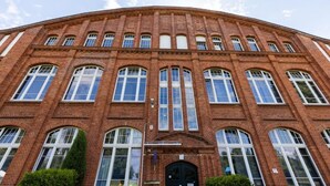 A large brick building with multiple arched windows and a central entrance. - Motel Home Wittenau (Berlin)