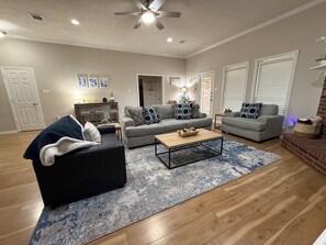A living room with two grey sofas, a black sofa, a wooden coffee table, and a ceiling fan.