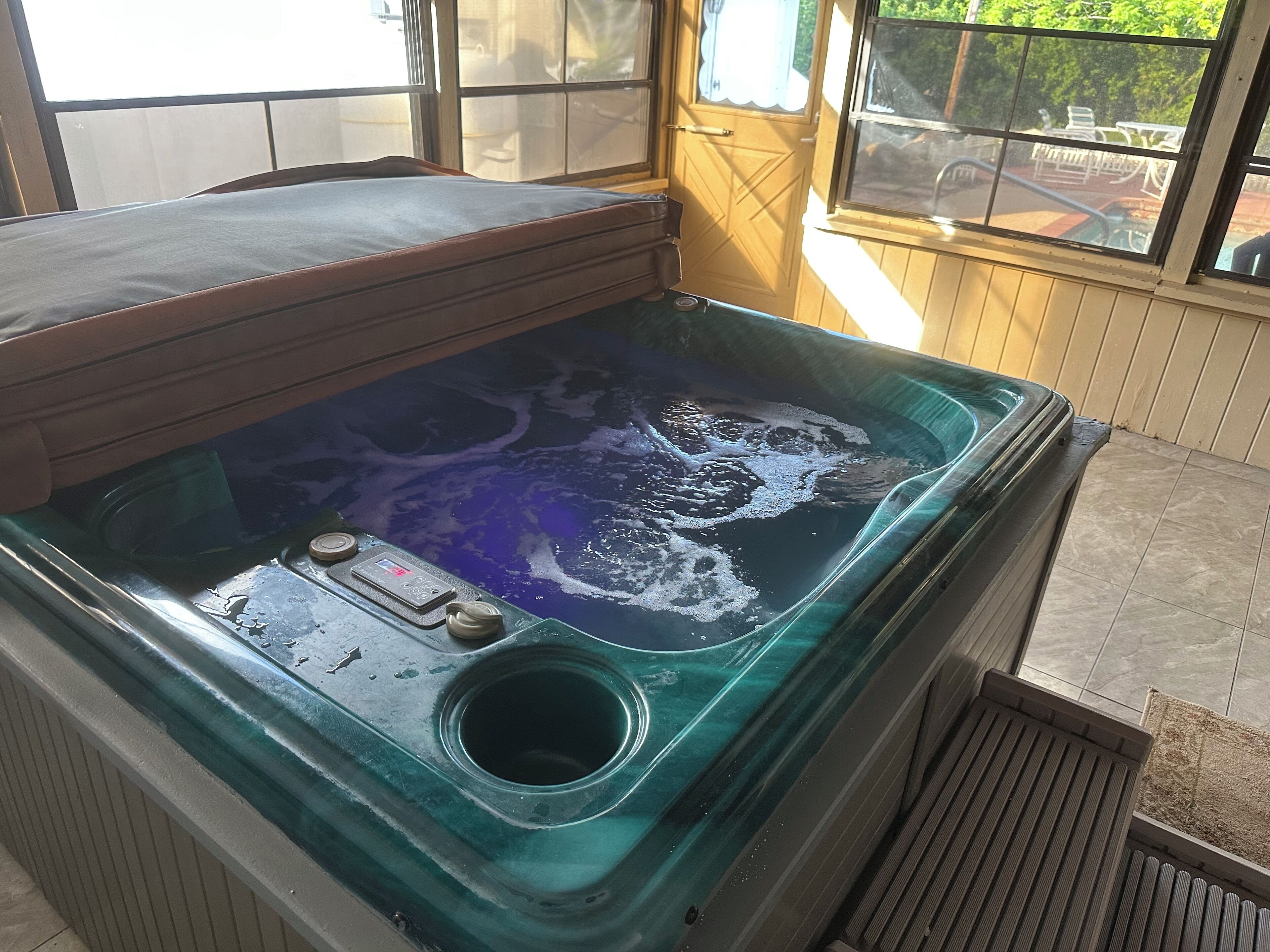 Un jacuzzi con panel de control, desagüe y zona de terraza de madera.