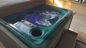 Ett bubbelbad med en kontrollpanel, ett avlopp och en träbelagd uteplats.
