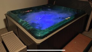 Ett bubbelbad med blått ljus, en kontrollpanel och en träbänk.