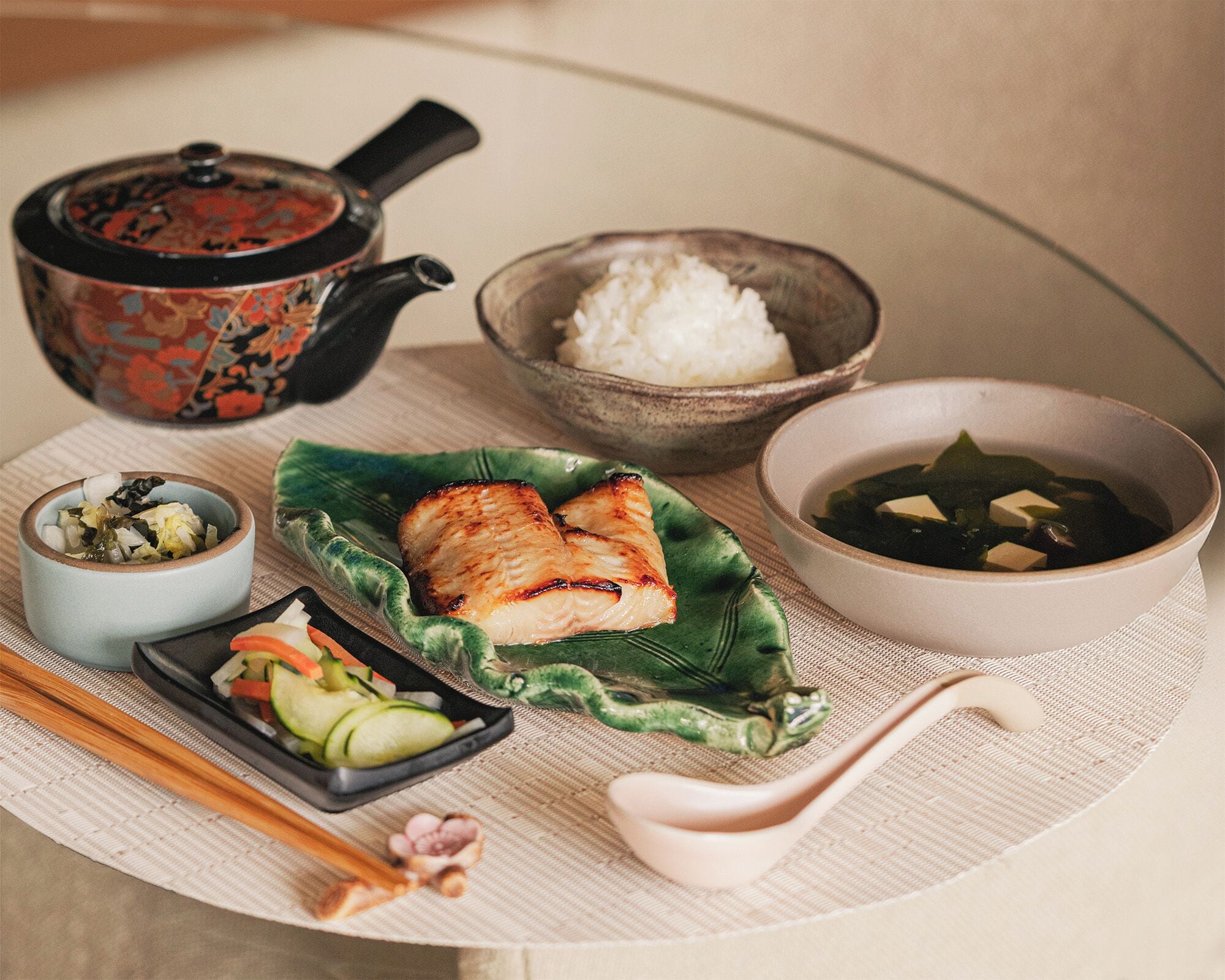 A traditional Japanese meal with rice, fish, and vegetables on a tatami mat.