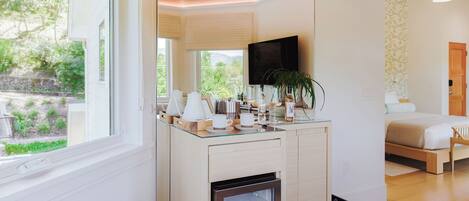 A modern kitchen with a built-in refrigerator, a dining area with a glass top table, and a bedroom with a bed and a TV.