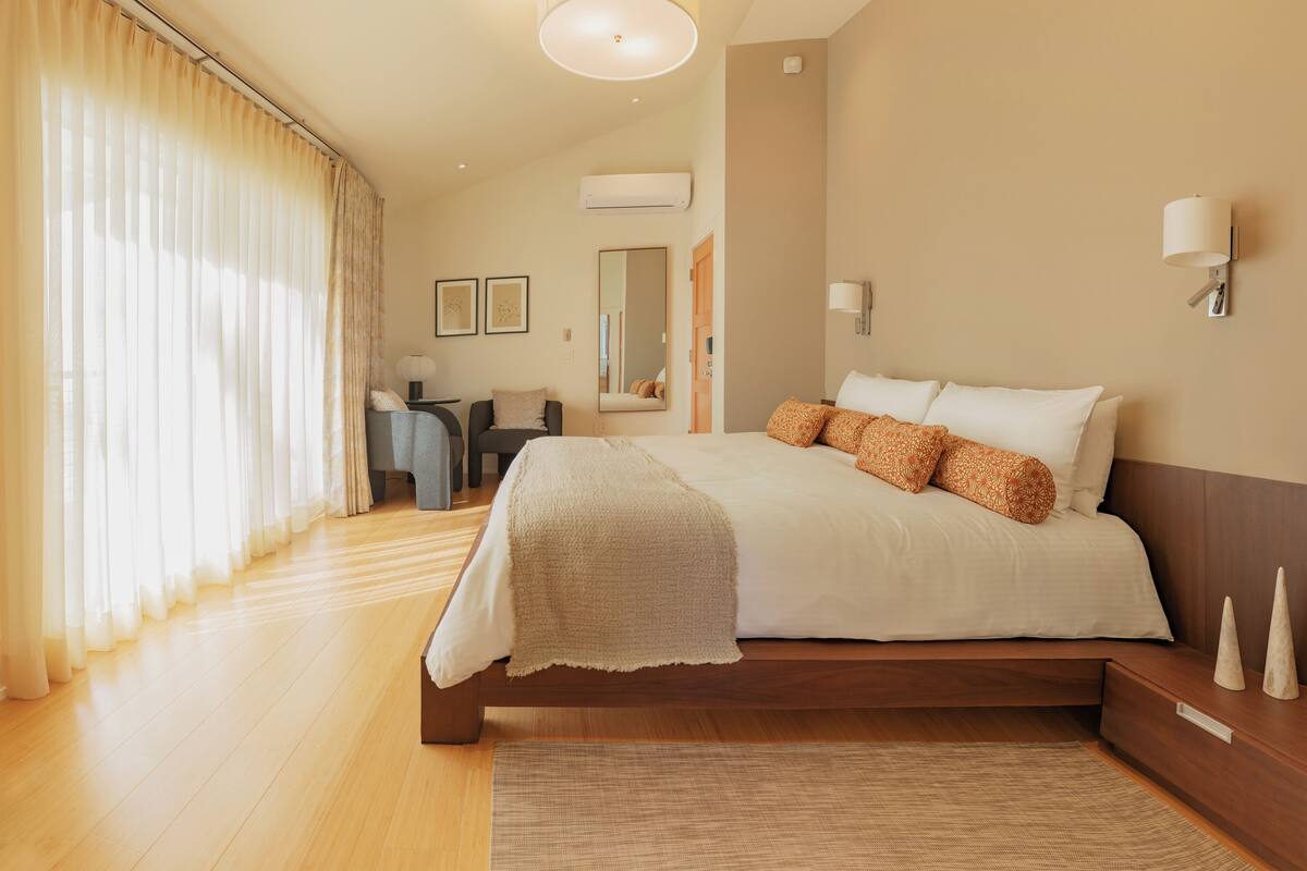 Una habitación de hotel moderna con una cama grande, mesitas de noche, un escritorio y una silla.