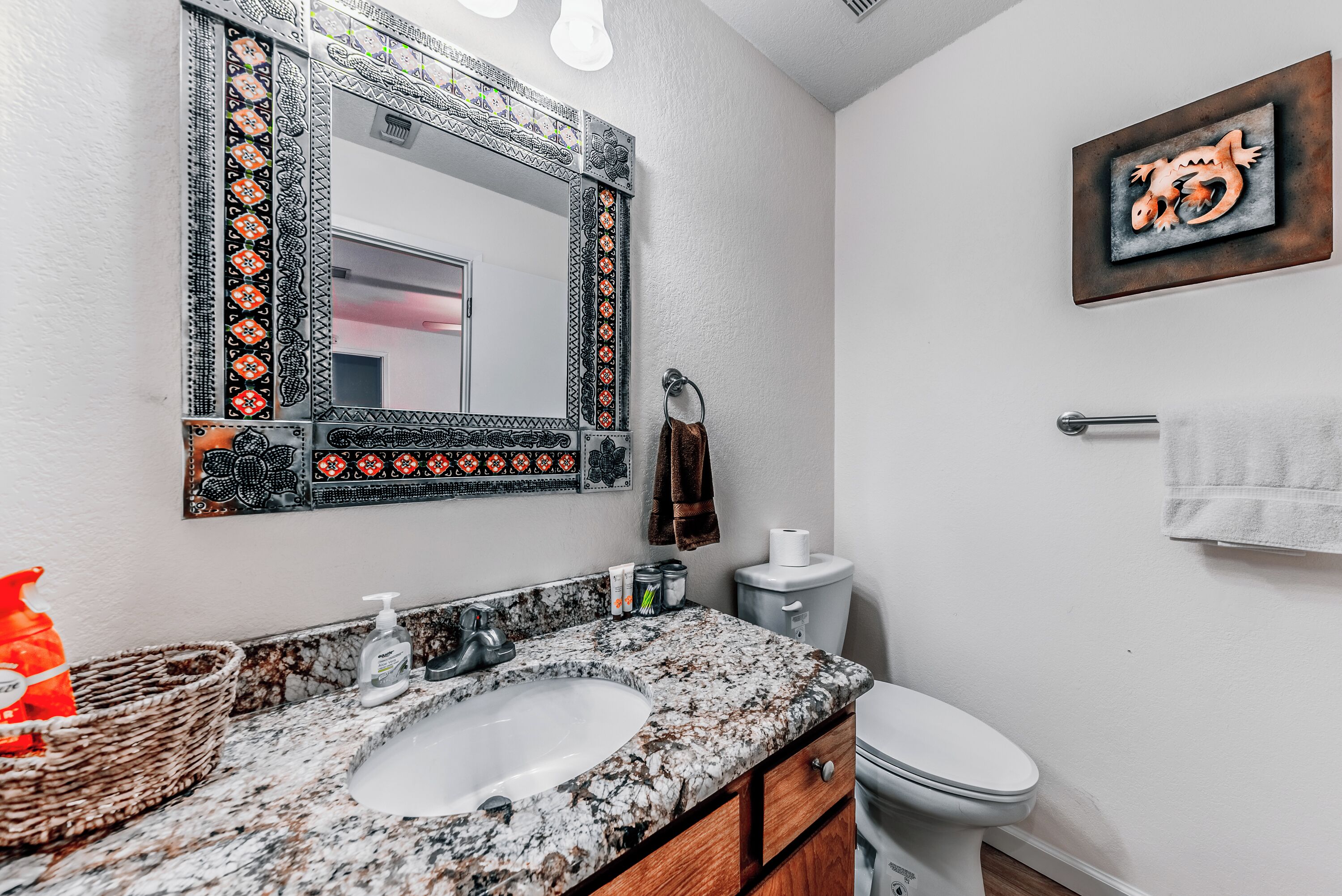 Une salle de bain avec un lavabo en granit, des toilettes et un miroir doté d’un cadre décoratif.