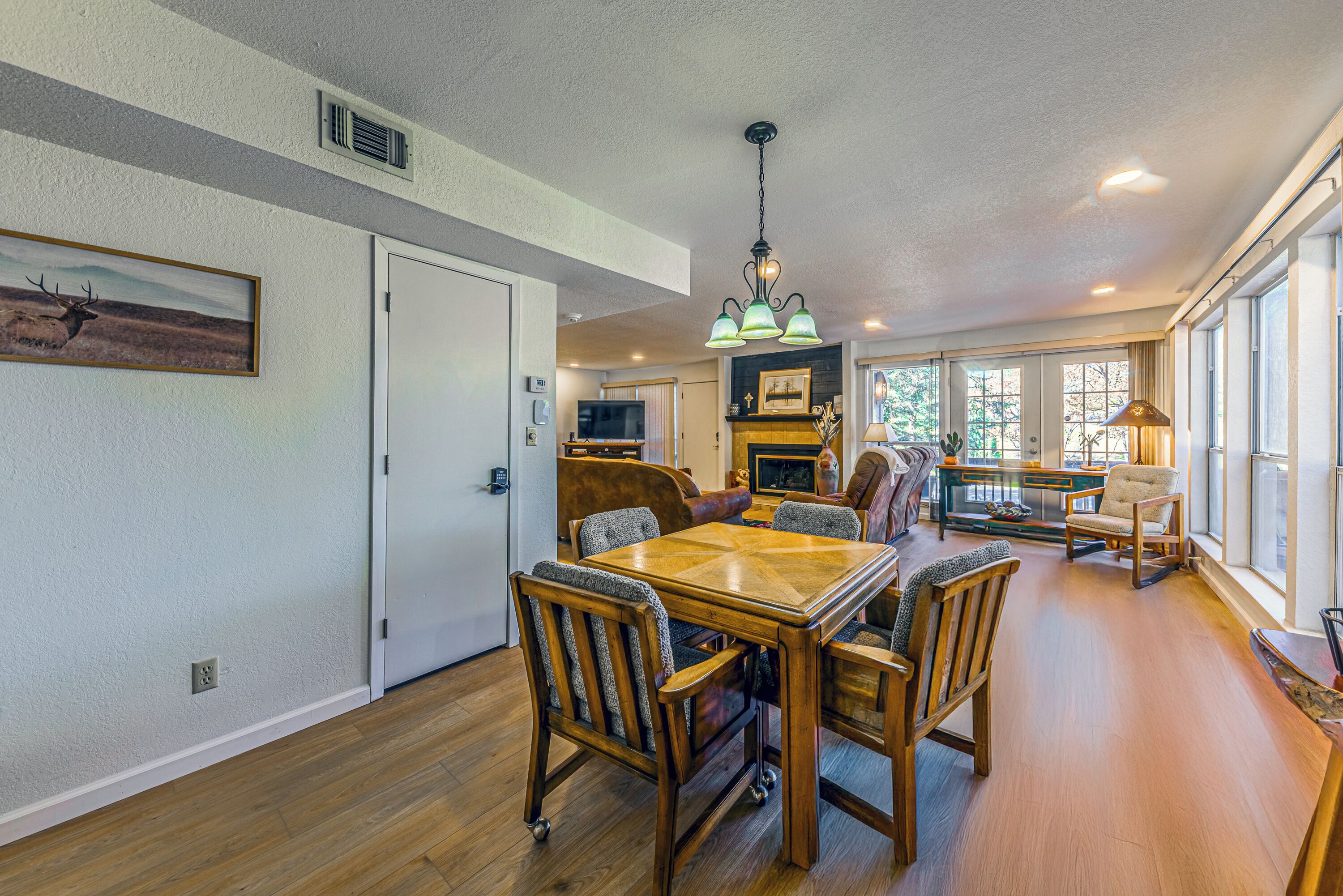 A dining area with a wooden table and chairs, a chandelier, and a fireplace.