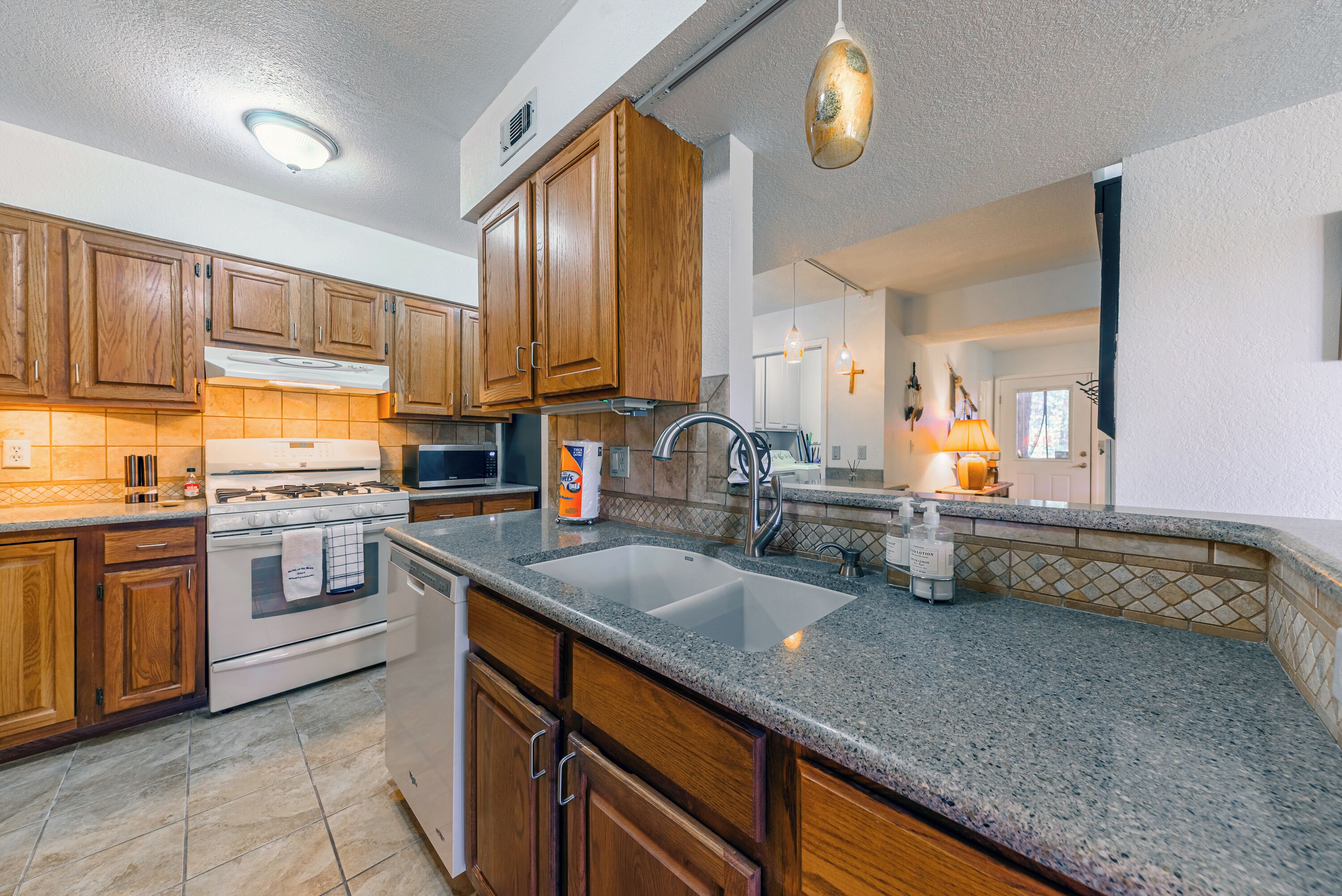 A kitchen with wooden cabinets, granite countertops, a double sink, and a stove.