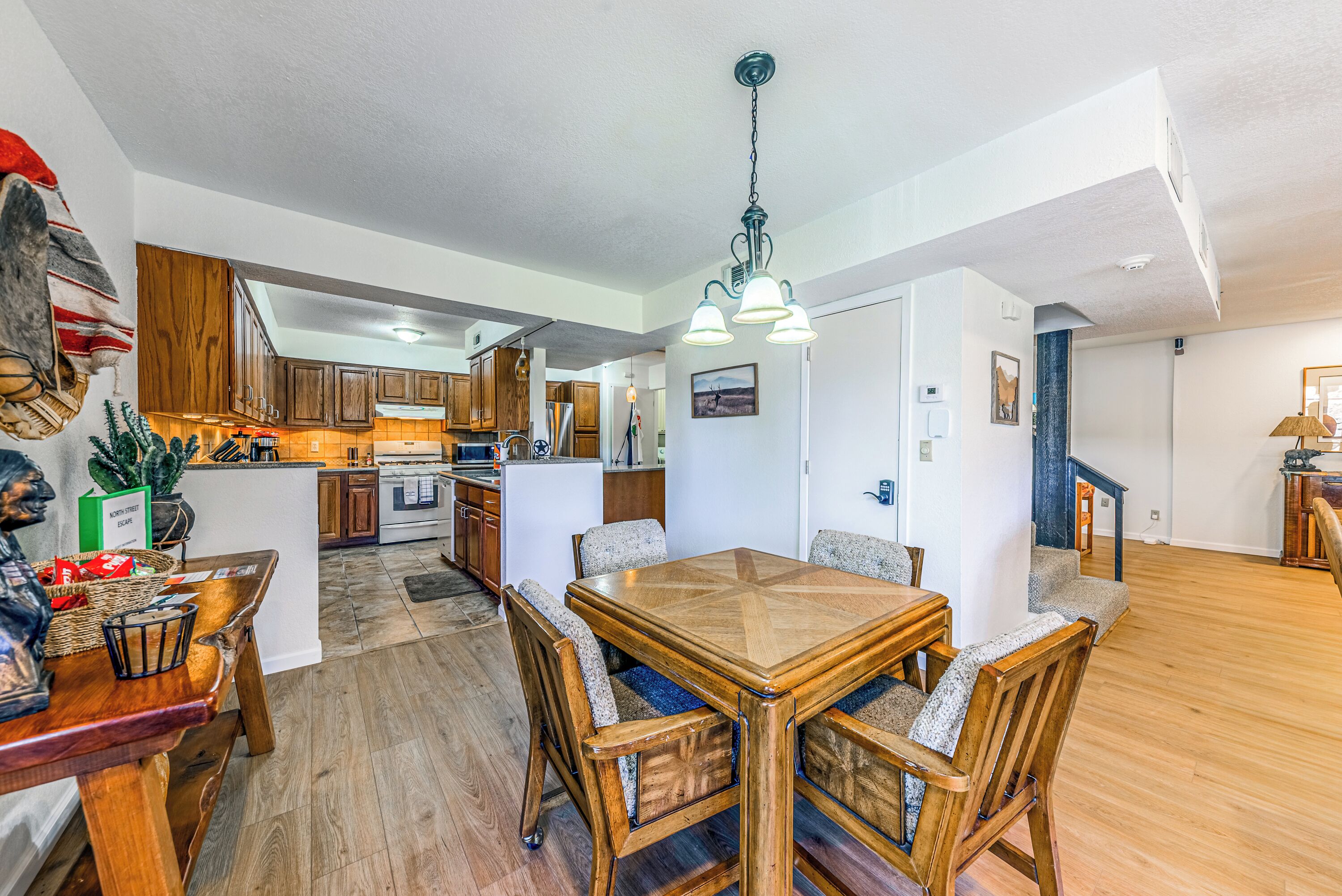 A spacious kitchen with wooden cabinets, a dining area with a wooden table and chairs, and a modern ceiling light fixture.
