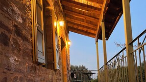 A wooden deck with a stone wall on one side, metal railing, and a view of the sky. - Pietra Rossa (Chios)