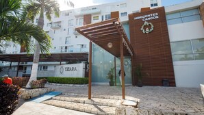 Ein Hotel Eingang mit moderner Fassade, einem überdachten Außenbereich und einem Schild mit der Aufschrift 'Horizontes Cancun'.