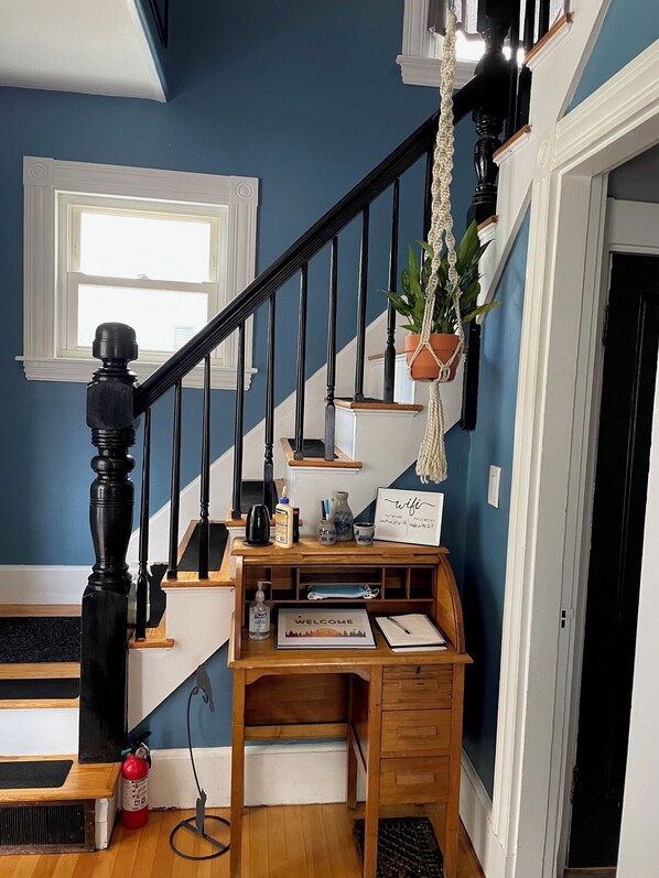 A staircase with a wooden desk and a hanging plant.
