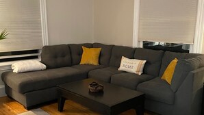 Una sala de estar con un sofá modular, una mesa de centro y una alfombra estampada.