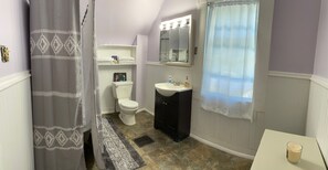 A bathroom with a toilet, sink, and mirror.