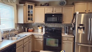A kitchen with beige cabinets, a black oven, a stainless steel refrigerator, a microwave, and a coffee maker. - Cute House on Lake Hartwell- Dock Access!
PETS ALLOWED! (Townville)