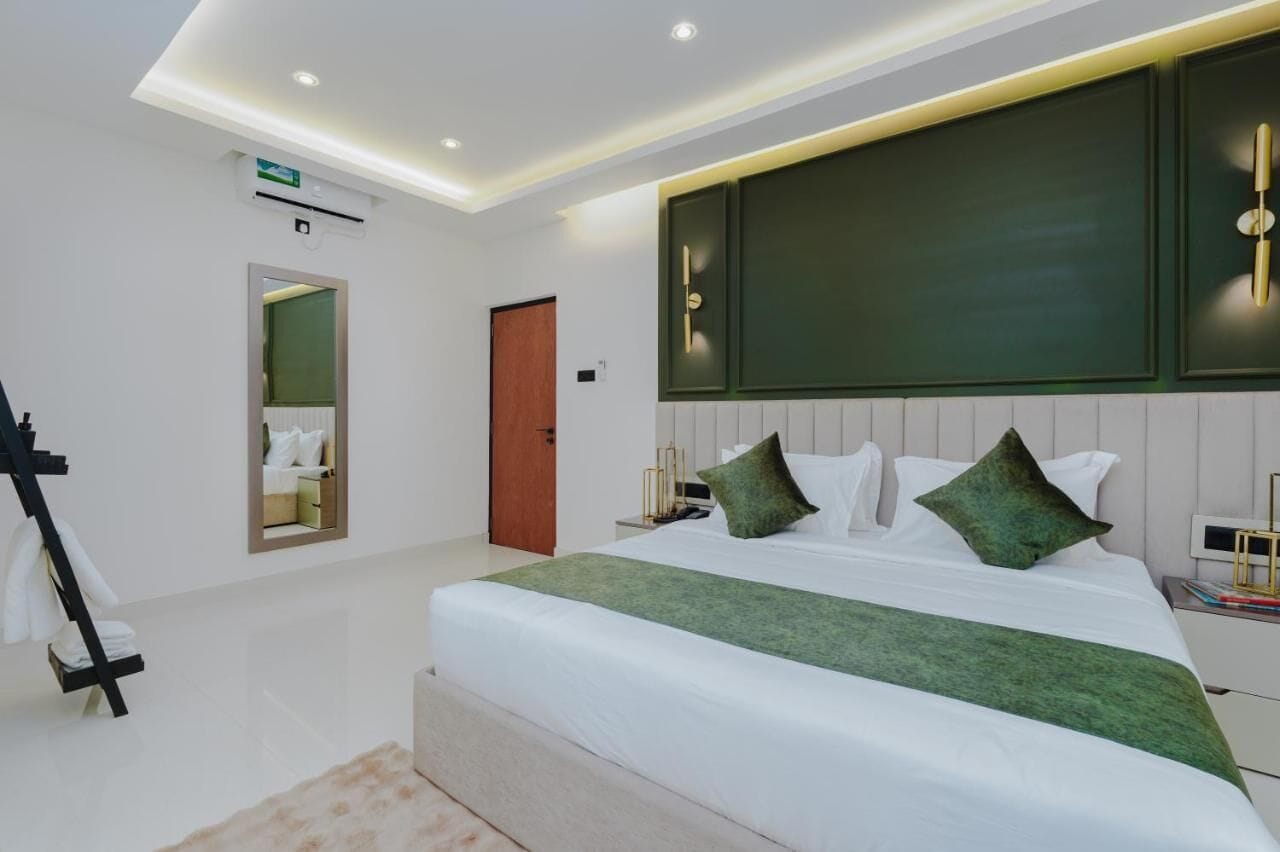 Una habitación de hotel moderna con una cama grande, una mesita de noche, un espejo y una puerta.