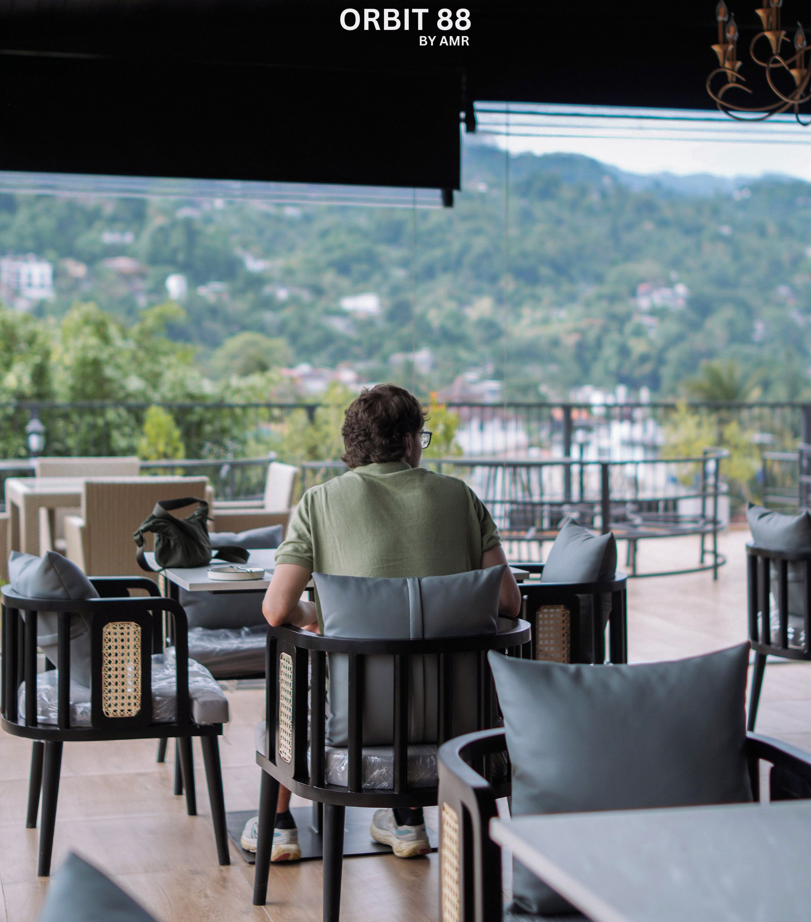 Una persona sentada en un café al aire libre con vistas a una colina.
