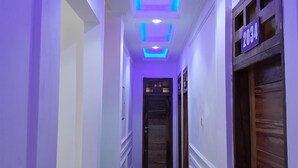 Un pasillo con iluminación morada, una puerta de madera y un letrero con número.