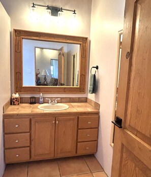 Un baño con tocador de madera, un espejo grande y un lavabo.