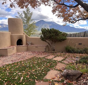 A courtyard with a stone pathway, a tree, and a mountain view. - Casita Vista Grande: Cozy Adobe with Epic Mountain Views! New on VRBO! Hot Tub (El Prado)