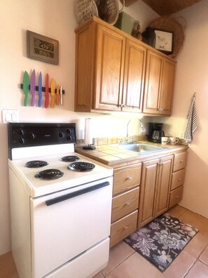 A kitchen with wooden cabinets, a white stove, and a tiled backsplash. - Casita Vista Grande: Cozy Adobe with Epic Mountain Views! New on VRBO! Hot Tub (El Prado)