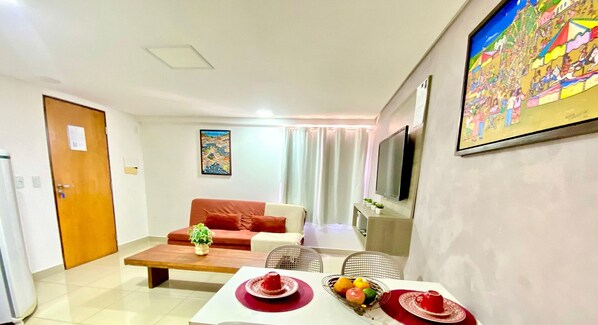 A living room with a sofa, a coffee table, a TV, and a painting on the wall.