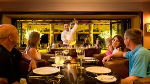 A restaurant with a bar area where a bartender is serving drinks. There are tables with diners and a view of the outdoors through large windows. - Stay at the Beautiful Villa De Palmar Islands of Loreto.   (loreto)