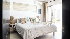 Ein Schlafzimmer mit Bett, Nachttischen, einem Fenster und Blick ins Freie.