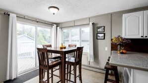Una cocina con mesa, sillas, encimera y vistas al exterior.