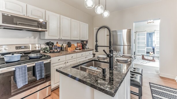 A modern kitchen with stainless steel appliances, white cabinetry, a marble countertop, and pendant lighting. - Pet-Friendly Apt  Fenced yard  Private Parking (Allentown)