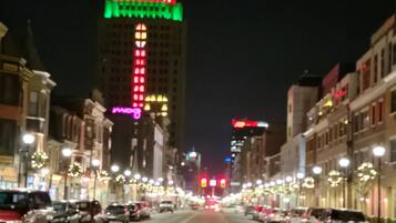 Une rue de la ville de nuit, avec des immeubles de chaque côté, des lampadaires et des voitures garées.