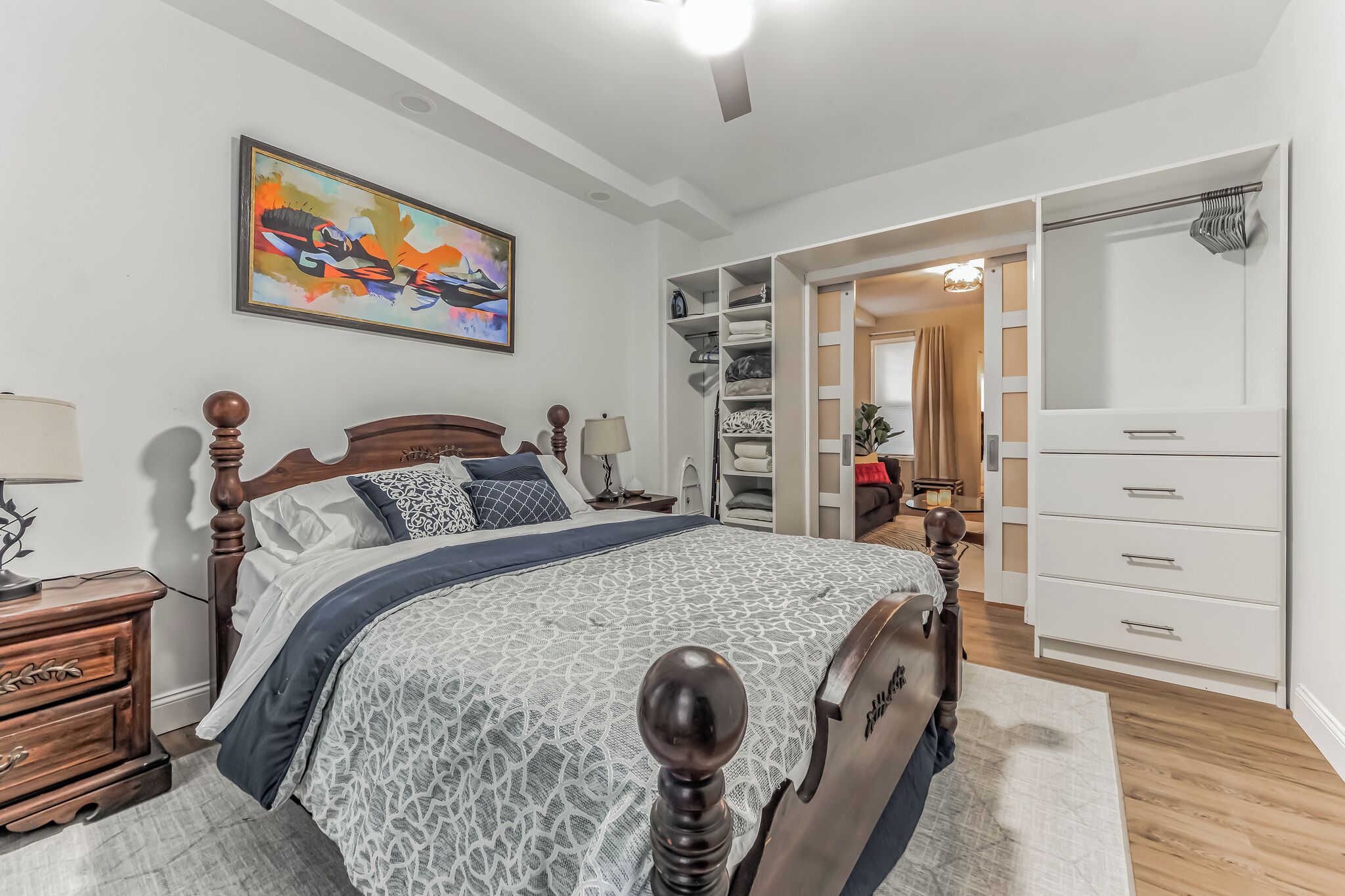 A bedroom with a bed, wooden headboard, bedside tables, a wardrobe, and a closet.