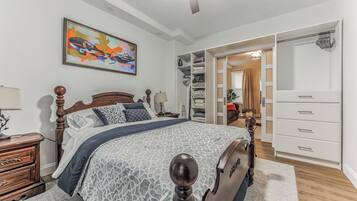 A bedroom with a bed, wooden headboard, bedside tables, a wardrobe, and a closet.