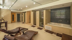 Un espacio moderno de spa con sillones de masaje, una bañera grande y una pared de mosaicos.