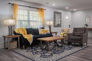 Un salon comprenant un canapé, des fauteuils, une table basse et un tapis à motifs.