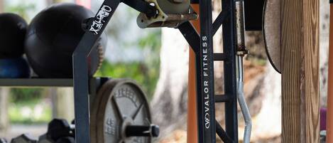 A weightlifting station with a bench press, adjustable dumbbells, and a weight stack.