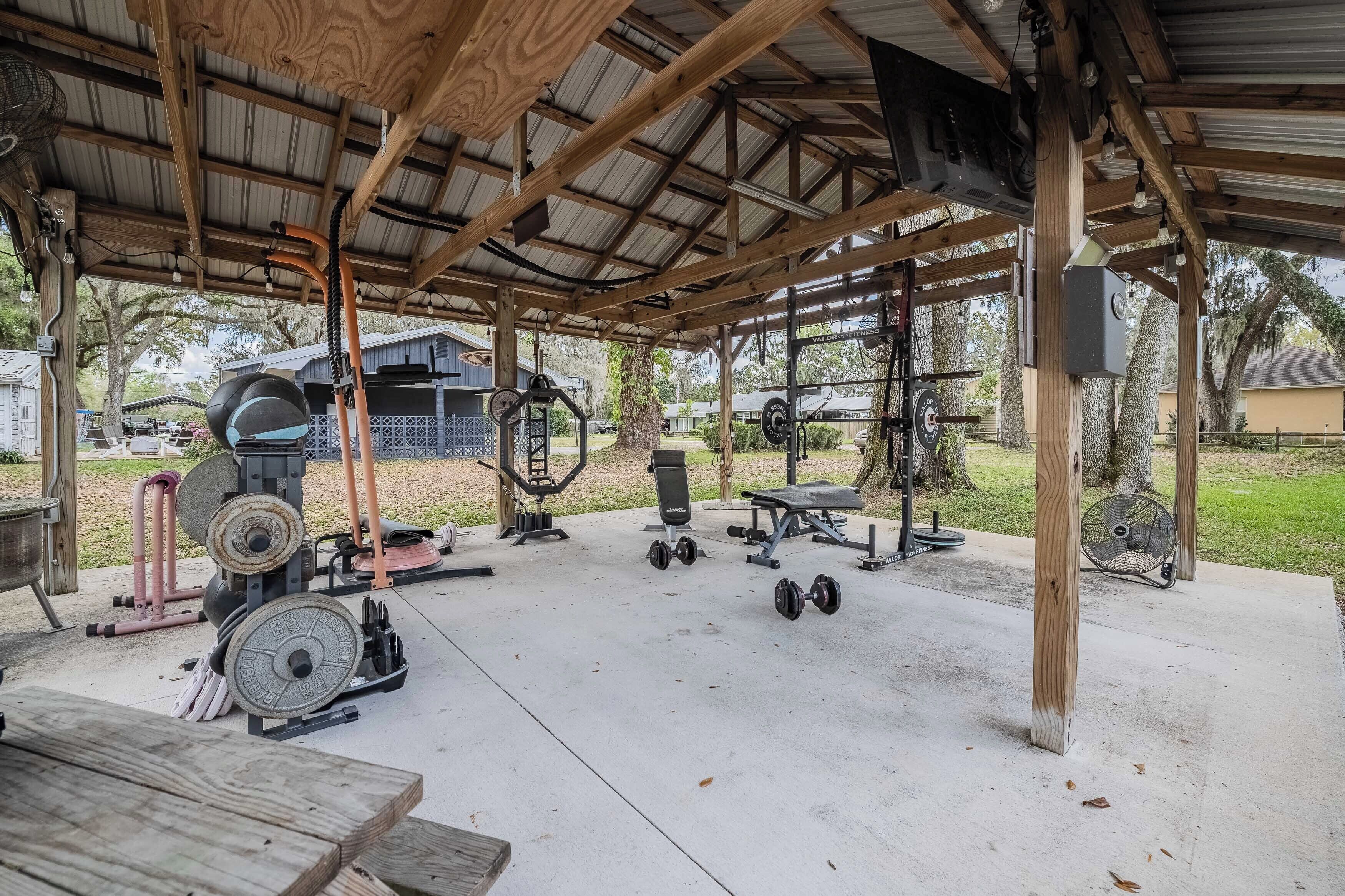 An outdoor gym with various exercise equipment, including weight machines and a bench.