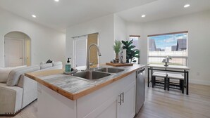 Una cocina moderna con una isla central, lavavajillas integrado y un comedor con mesa y bancos.
