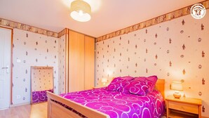 Un dormitorio con cama, mesita de noche, armario y puerta.