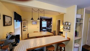A kitchen with a tiled backsplash, wooden bar stools, a dining table, and a hanging light fixture. - 162 Peach Perfectly Located inside Lakeside! (Lakeside)