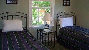 A bedroom with two single beds, a small table with a lamp, and a window with a view of greenery. - 343 Oak Ave in Lakeside (Lakeside)